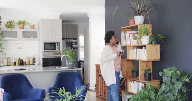 Woman Talking on Phone While Holding Coffee Cup in Modern Living Room - Download Free Stock Images Pikwizard.com