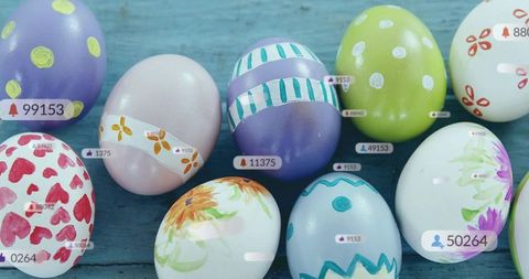 Displaying pastel hand-painted easter eggs on rustic blue wood with social media tag overlays