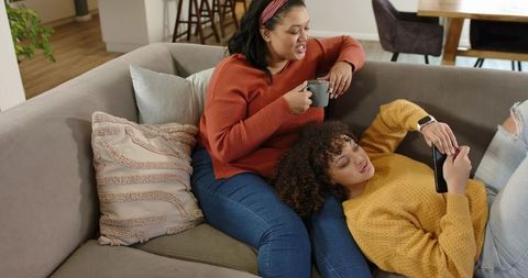 African American Mother and Adult Daughter Relaxing Together on Couch in Cozy Home