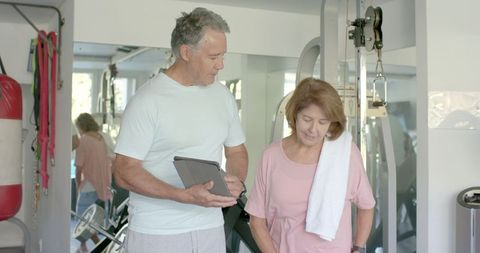 Senior couple discussing fitness plan with tablet in home gym