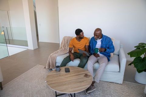 Father and son bonding time using tablet in modern home interior