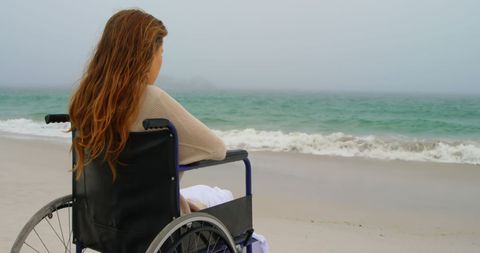 A woman in a wheelchair gazing at the expansive ocean from the comfort of a sandy beach. The serene setting conveys themes of peace, reflection, and freedom. This image is suitable for promoting accessibility in nature, mental health awareness, or travel destinations highlighting inclusivity and relaxation.