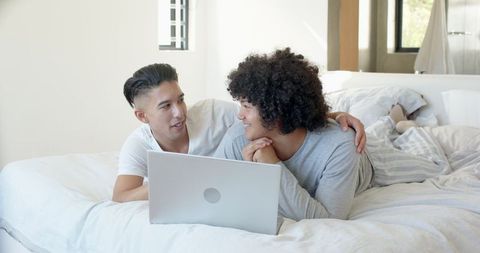 Couple Relaxing with Laptop on Cozy Bed