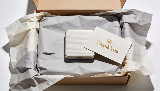 Unboxing minimalist gift box with ribbed compact device and gold-foil thank you card
