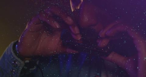 Indian man's hands holding smartphone horizontally in moody purple-blue low light
