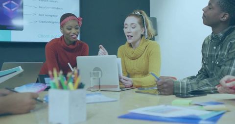 Team collaborating around laptop during creative meeting with presentation slides