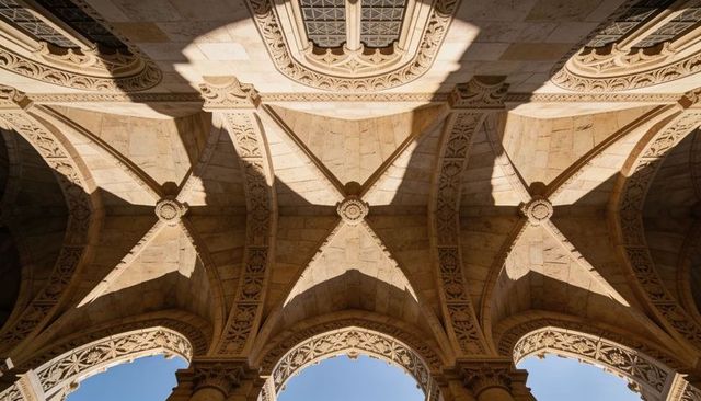 Sunlit ornate ribbed vaults in cloister arcade featuring carved stone keystones and arches