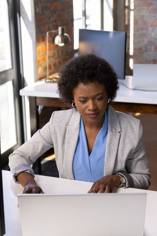 Confident Professional Woman Engaged in Work on Laptop at Modern Office