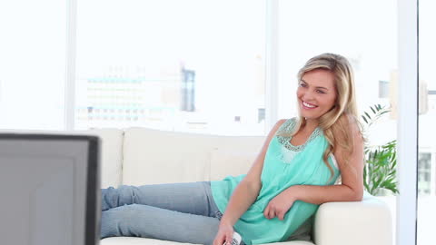 Smiling Woman Watching TV Relaxing on Sofa in Living Room