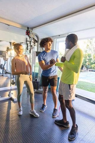 Friends celebrating workout success in bright home gym, smiling, clasping hands