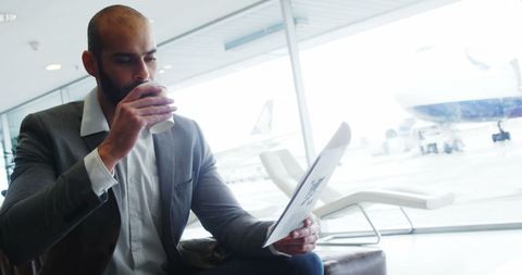 Businessman Having Coffee While Reviewing Documents at Airport Lounge
