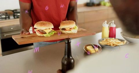 Presenting juicy cheeseburgers on wooden board with fries and condiments in home kitchen