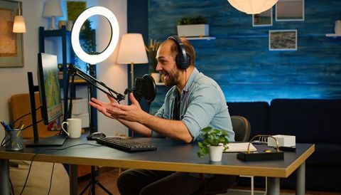 Content creator recording podcast in cozy home studio with ring light and microphone