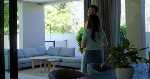 Asian couple embracing by open sliding door in modern minimalist living room with patio