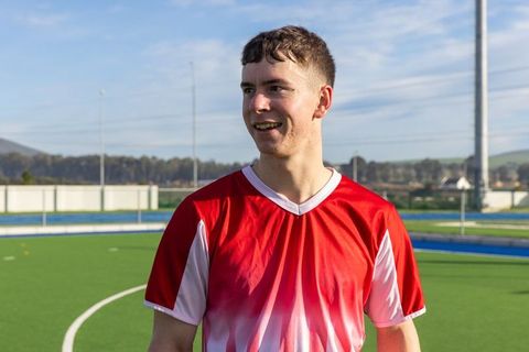 Young Male Athlete Standing on Outdoor Hockey Field Smiling