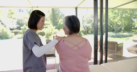 Physiotherapist Assisting Senior Woman with Shoulder Exercises