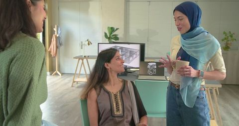 Multicultural female designers collaborating over floor plans in modern studio