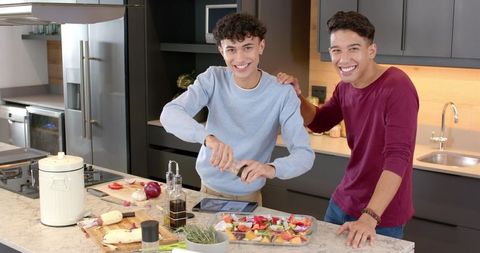 Two friends cooking together in modern kitchen, smiling collaboration