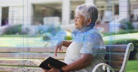 Senior asian woman reading on bench in sunny courtyard with digital network overlay, calm