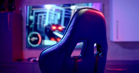 Modern gaming chair in vivid lighting with racing game across screen