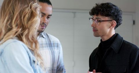 Young professionals standing and talking during informal office meeting and collaboration