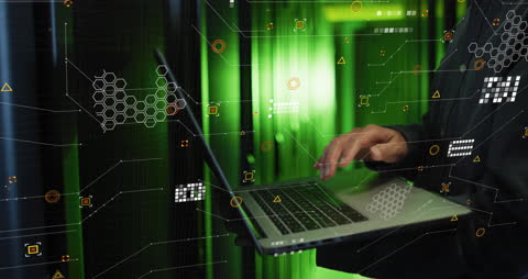 IT Engineer Analyzing Data on Laptop Among Server Arrays