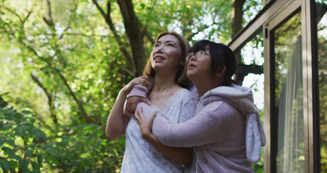 Asian mother and daughter embracing in garden and smiling. at home in isolation during quarantine lockdown.