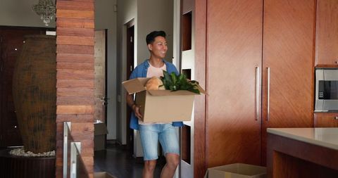 Happy Man Moving Into New Home Unpacking Box Full of Household Items