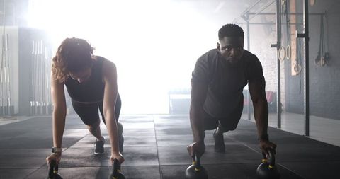 Diverse athletes performing kettlebell push-ups in gym
