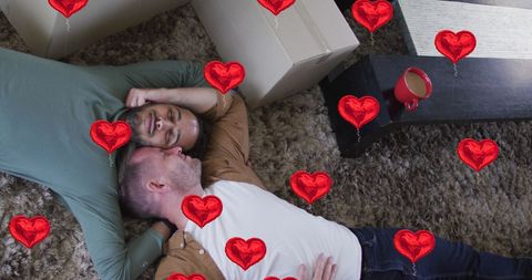 Diverse gay couple relaxing with heart icons for pride