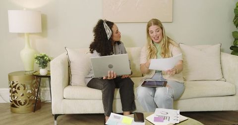 Female Colleagues Collaborating with Technology in Cozy Living Room