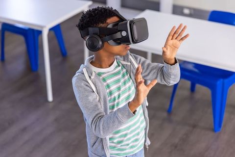 African american boy exploring vr in classroom wearing headset