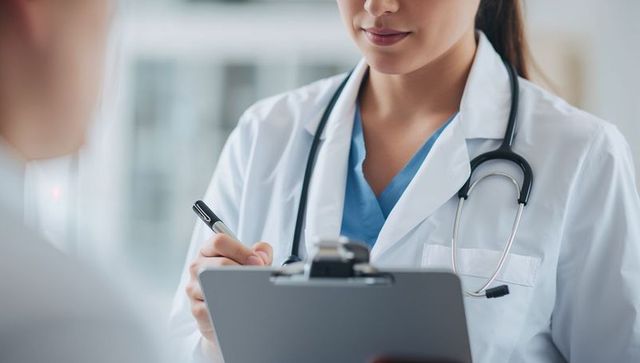 Female doctor consulting patient with clipboard and stethoscope in clinic