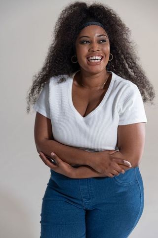Confident african american woman smiling in casual v-neck top and jeans, curly hair