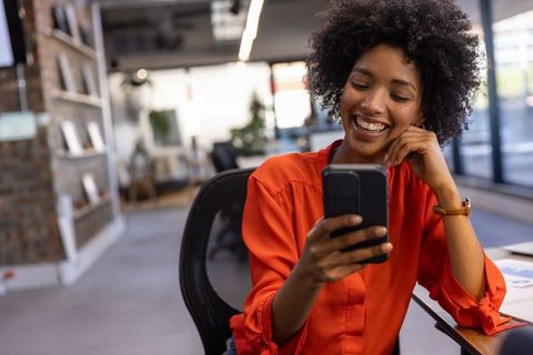 Smiling Professional Using Smartphone at Modern Office Desk