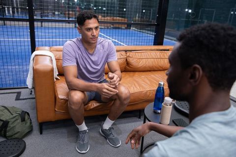 African-american teammates discussing strategy and recovery on lounge couch after training