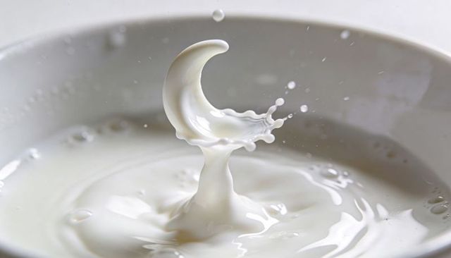Crescent milk splash forming liquid crown rising from ceramic bowl