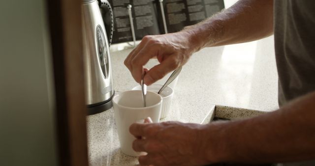 Person Stirring Coffee in Kitchen Near Coffee Maker - Download Free Stock Images Pikwizard.com