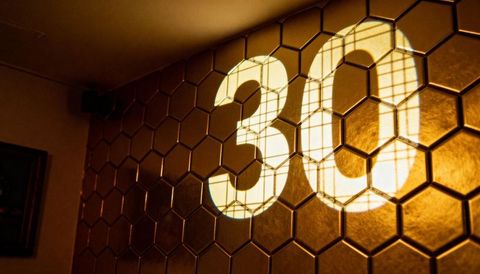 Projecting number 30 on gold hex tile wall, reflective honeycomb pattern with window grid