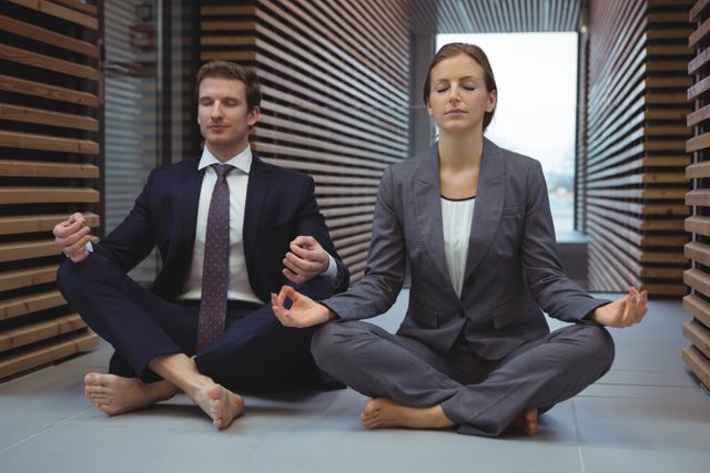 Businesspeople performing yoga in the corridor at office
