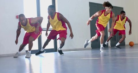 Group of athletes practicing defensive slide drill in basketball gym
