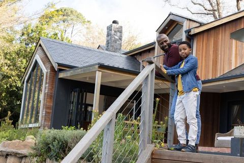 African american father and son enjoying modern wood-clad home exterior and garden