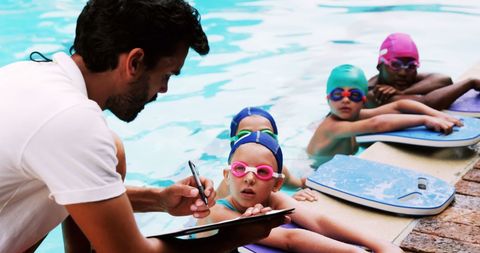 Diverse group of children with swim instructor by poolside