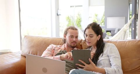 Couple Engaging with Digital Tablet on Couch at Home