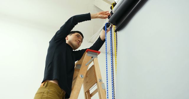 Man Adjusting Photography Equipment on Ladder in Studio - Download Free Stock Images Pikwizard.com