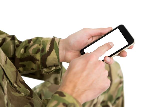 Soldier in camouflage uniform using a smartphone, focusing on the hand and device against a white background. Useful for themes related to military technology, communication, modern warfare, and digital connectivity in armed forces.
