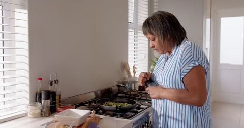 Senior Woman Cooking Vegetables in Bright Kitchen