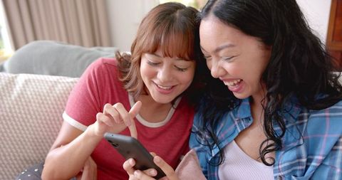 Two female friends sharing moments with smartphone