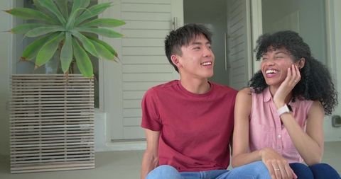 Young couple laughing on porch steps near large succulent and modern louvered door