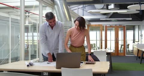 Business Team Collaborating Over Blueprint in Modern Office Space